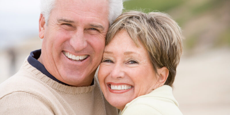 A smiling older couple on the beach after restorative dental treatments in Solana Beach.