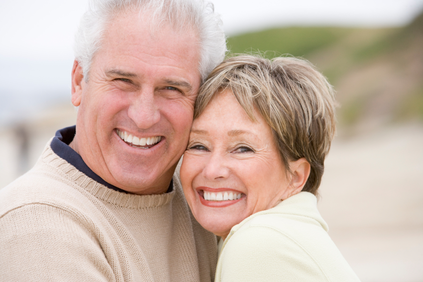 A smiling older couple on the beach after restorative dental treatments in Solana Beach.